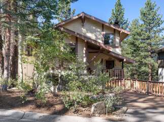 Nestled amidst tall pine trees, this charming home offers a rustic mountain retreat.