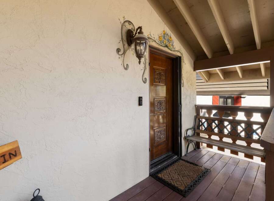 Welcome guests to this charming property with a beautifully carved wooden front door, adorned with decorative floral artwork and a classic lantern.