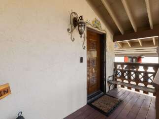 Welcome guests to this charming property with a beautifully carved wooden front door, adorned with decorative floral artwork and a classic lantern.