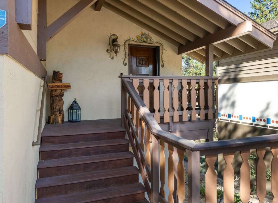 Welcome to this charming cabin, featuring a rustic wooden bear statue and a decorative lantern on the porch.