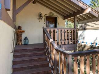 Welcome to this charming cabin, featuring a rustic wooden bear statue and a decorative lantern on the porch.