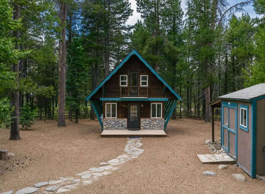 Escape to this charming A-frame cabin nestled amongst tall pine trees, offering a serene mountain retreat.