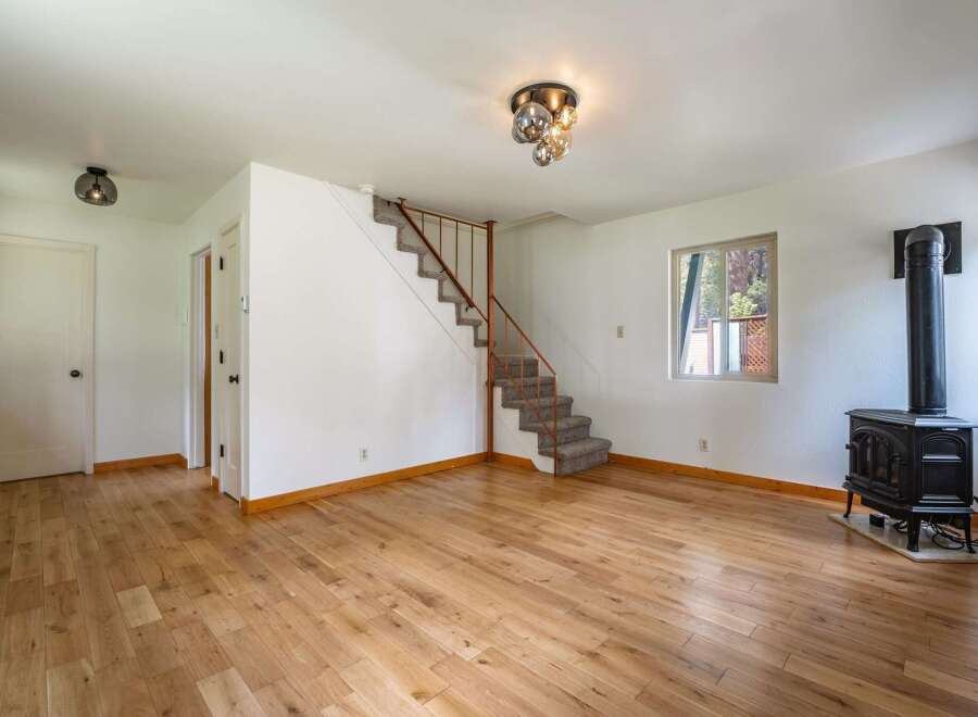 Step into this inviting living space featuring warm hardwood floors and a cozy wood-burning stove, perfect for chilly evenings.