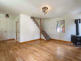 Step into this inviting living space featuring warm hardwood floors and a cozy wood-burning stove, perfect for chilly evenings.
