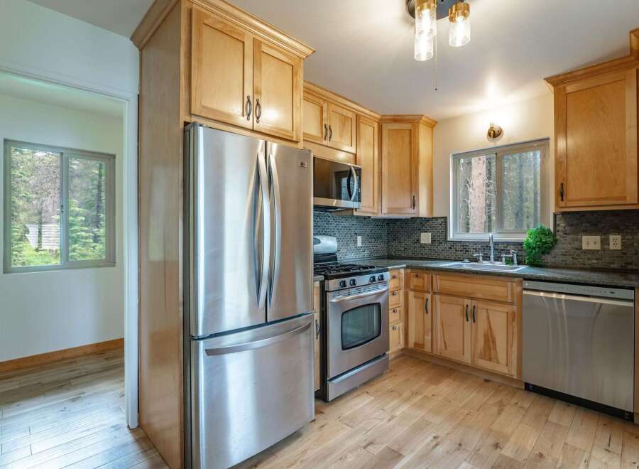 Discover this charming kitchen featuring light wood cabinetry and a sleek stainless steel refrigerator.
