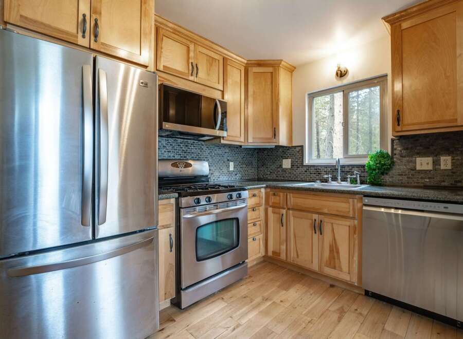 This kitchen boasts modern stainless steel appliances, including a refrigerator, gas range, and dishwasher, perfect for any home chef.