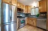 This kitchen boasts modern stainless steel appliances, including a refrigerator, gas range, and dishwasher, perfect for any home chef.