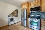 This kitchen features a stainless steel refrigerator, a gas range with a microwave above, and a stacked washer and dryer tucked into a convenient alcove.