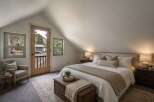 Experience cozy mountain living in this charming bedroom featuring a comfortable king-size bed, a rustic wooden trunk for storage, and a plush armchair perfect for reading.