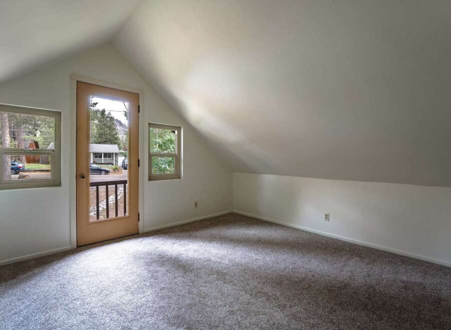 Discover this charming attic room, bathed in natural light from multiple windows and a glass-paneled door.