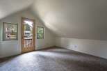Discover this charming attic room, bathed in natural light from multiple windows and a glass-paneled door.