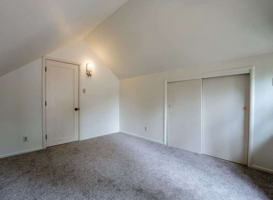 Discover this charming attic bedroom, featuring a vaulted ceiling and ample natural light.