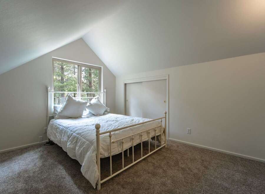 This charming bedroom features a cozy white metal bed adorned with plush pillows, perfect for restful nights.