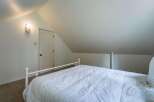 Discover cozy charm in this attic bedroom, featuring a comfortable white comforter on a classic metal bed frame.