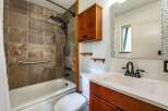 This updated bathroom features a stylish tiled shower and tub surround, complemented by a modern black showerhead and fixtures.