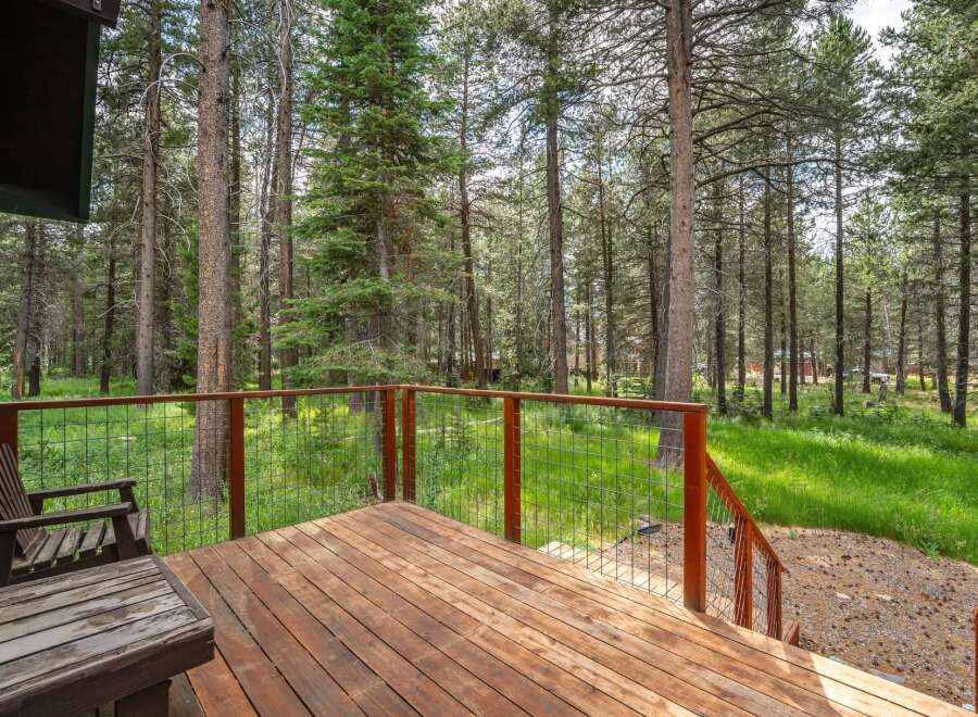Enjoy the serene mountain lifestyle from this charming deck, nestled amongst towering pine trees.