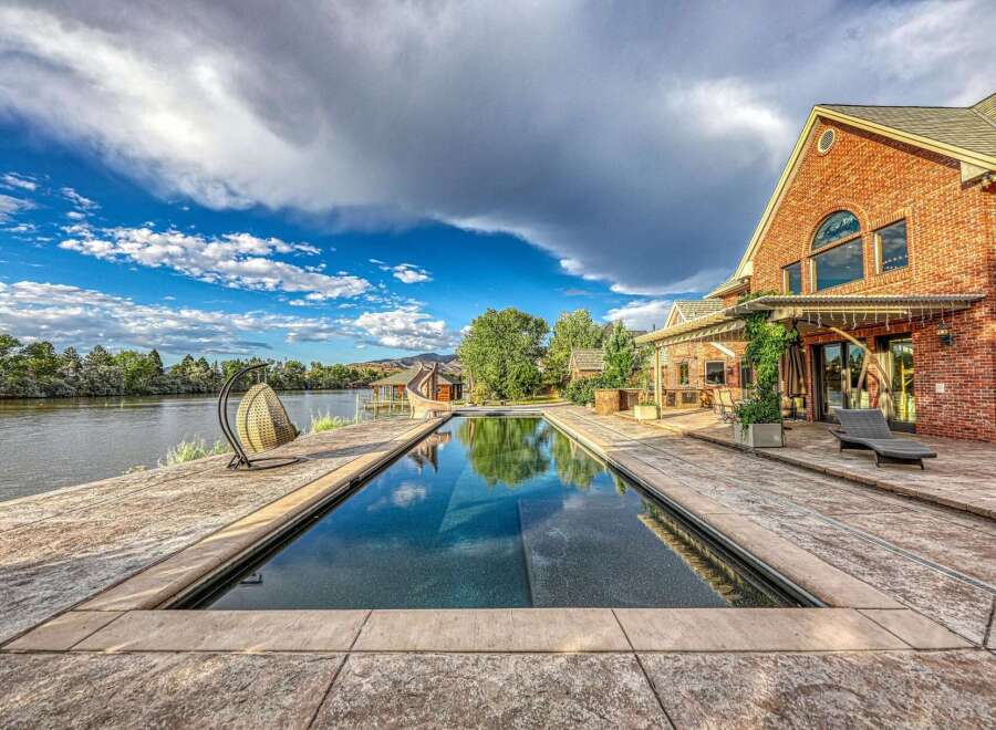 Experience luxurious waterfront living with this stunning property featuring a rectangular swimming pool overlooking a serene lake.