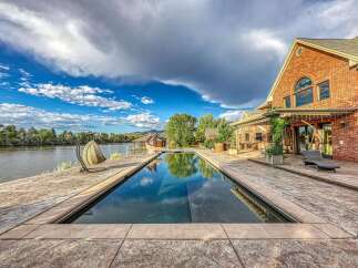 Experience luxurious waterfront living with this stunning property featuring a rectangular swimming pool overlooking a serene lake.