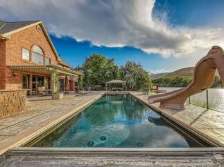 Experience luxury outdoor living with this stunning property featuring a large, rectangular swimming pool and an attached slide for endless fun.
