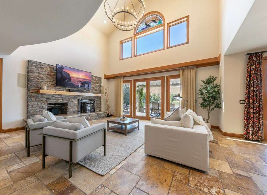 Experience luxurious living in this stunning great room featuring a floor-to-ceiling stone fireplace and a soaring vaulted ceiling.