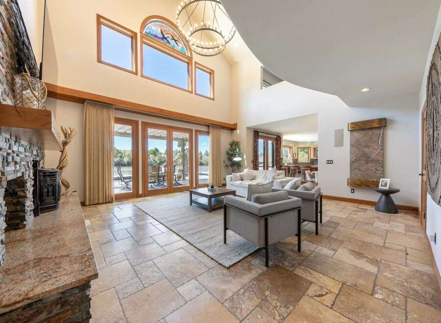 Experience luxurious living in this grand great room, featuring a stunning floor-to-ceiling stone fireplace and expansive windows that flood the space with natural light.