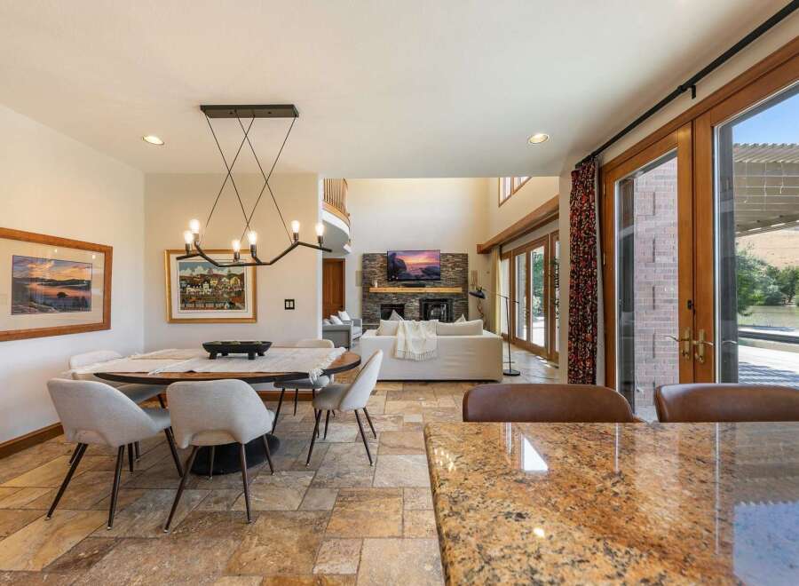 Experience luxurious open-concept living with this stunning dining and living area, featuring a modern chandelier and a cozy fireplace.