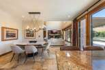Experience luxurious open-concept living with this stunning dining and living area, featuring a modern chandelier and a cozy fireplace.