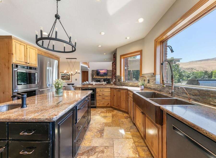 Experience luxury in this stunning kitchen featuring a large granite island with a sink and a spacious farmhouse sink overlooking breathtaking views.