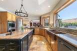 Experience luxury in this stunning kitchen featuring a large granite island with a sink and a spacious farmhouse sink overlooking breathtaking views.