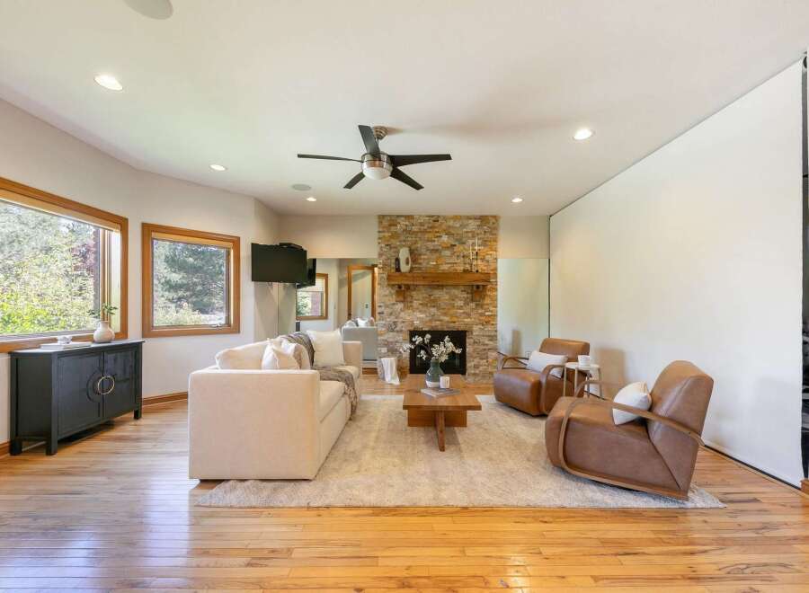 Experience modern living in this spacious living room, featuring a stunning stone fireplace and a cozy sectional sofa perfect for relaxation.