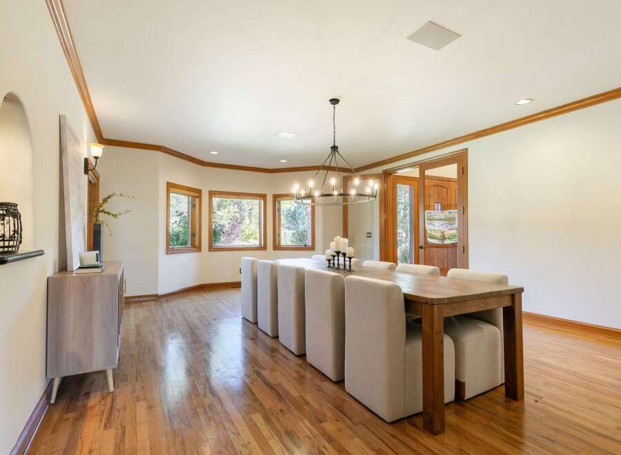 This elegant dining room features a large wooden table with upholstered chairs, perfect for hosting gatherings.