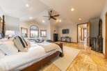 Experience luxury in this spacious master suite, featuring a grand four-poster bed and a cozy seating area by the arched stained-glass window.