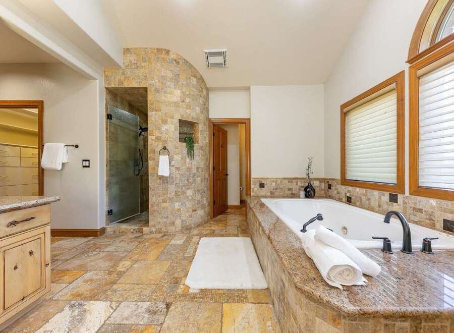 Indulge in luxury in this stunning master bathroom featuring a spacious walk-in shower with a curved, tiled accent wall and a deep soaking tub perfect for relaxation.