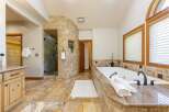 Indulge in luxury in this stunning master bathroom featuring a spacious walk-in shower with a curved, tiled accent wall and a deep soaking tub perfect for relaxation.