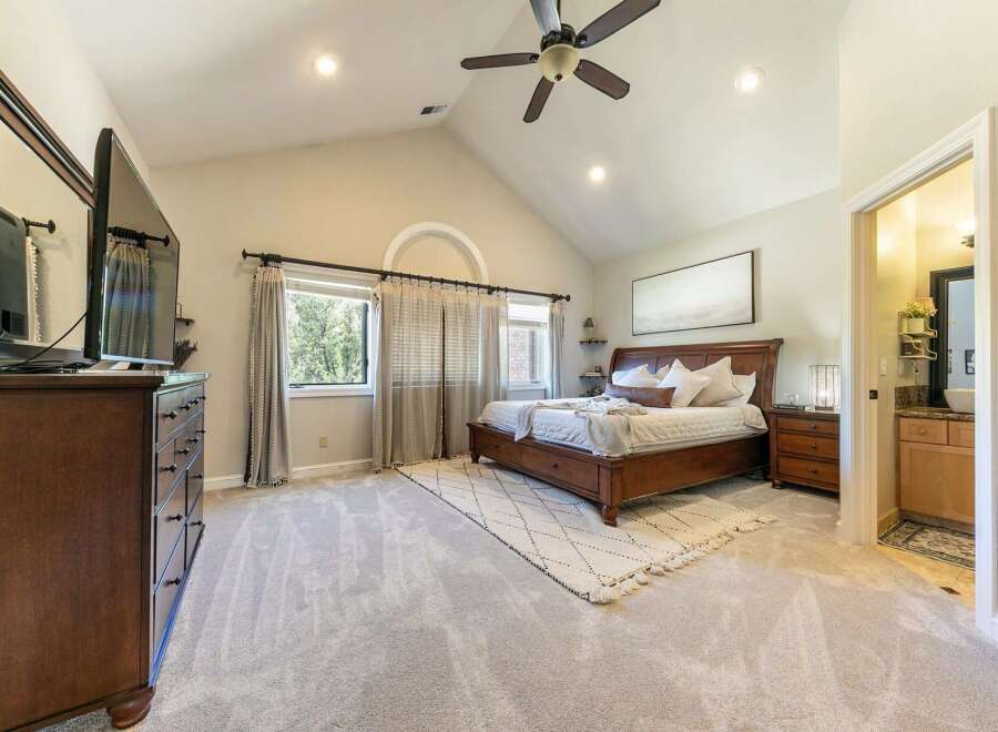Experience luxury and comfort in this spacious master bedroom, featuring a vaulted ceiling with a ceiling fan and recessed lighting.