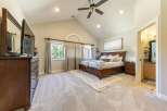 Experience luxury and comfort in this spacious master bedroom, featuring a vaulted ceiling with a ceiling fan and recessed lighting.