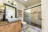 This modern bathroom features a spacious vanity with a vessel sink and granite countertops, complemented by a large framed mirror.