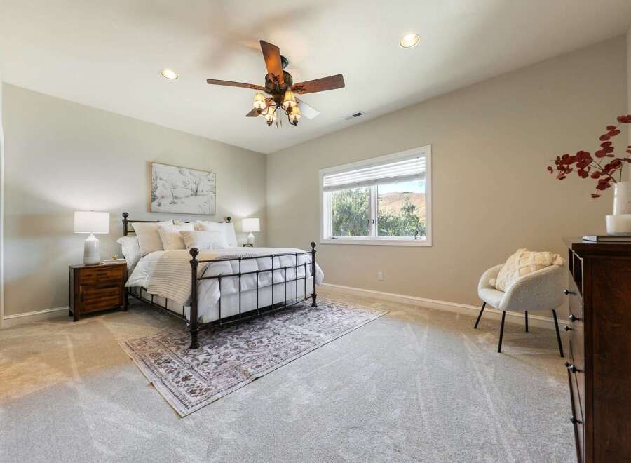 Experience comfort and style in this beautifully appointed bedroom, featuring a plush carpet, elegant metal-frame bed, and a serene landscape view from the window.