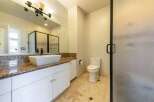 This spacious bathroom features a modern vessel sink atop a granite countertop with ample storage below.