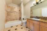 This beautifully appointed bathroom features a luxurious travertine tile shower and bathtub surround, complemented by a decorative mosaic tile accent.