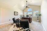 This executive home office features a grand wooden desk with a leather chair, complemented by two plush leather armchairs and a striking cowhide rug.