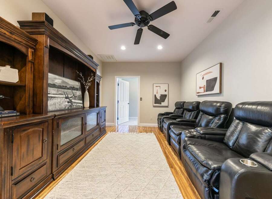 Experience ultimate relaxation in this home theater, featuring plush black leather recliners with built-in cup holders.