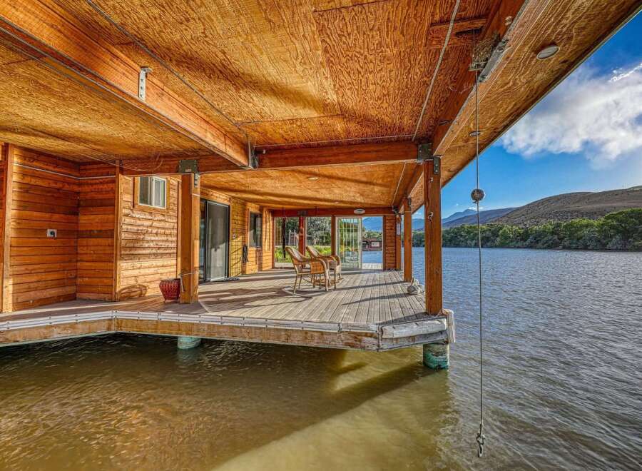 Experience waterfront living at its finest with this stunning property featuring a spacious wooden deck extending over the water.