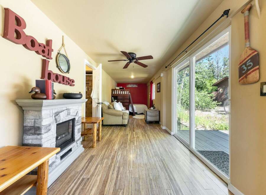 Discover this charming lakeside retreat featuring a cozy living area with a stone fireplace and a bunk bed setup, perfect for accommodating guests.