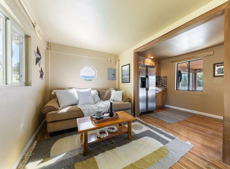 Cozy living space featuring a comfortable sofa, a rustic coffee table, and a functional kitchen area with stainless steel appliances.
