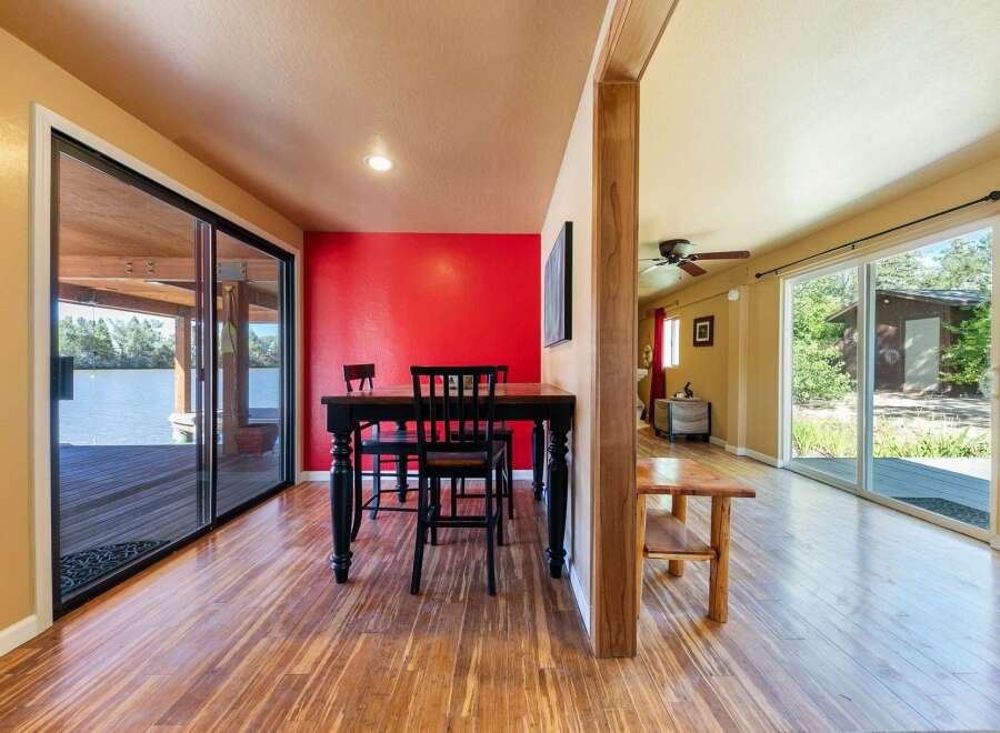 Enjoy waterfront living with this stunning property featuring a spacious dining area with a bright red accent wall and direct access to a deck overlooking the water.