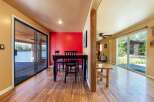 Enjoy waterfront living with this stunning property featuring a spacious dining area with a bright red accent wall and direct access to a deck overlooking the water.