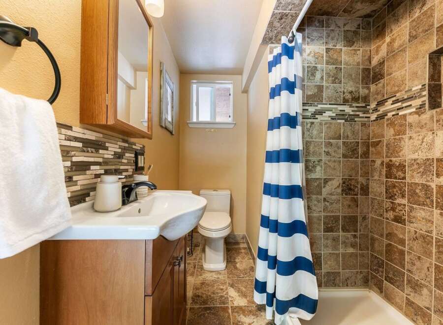 This charming bathroom features a stylish vanity with a mosaic tile backsplash, complemented by a modern sink and faucet.