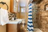 This charming bathroom features a stylish vanity with a mosaic tile backsplash, complemented by a modern sink and faucet.