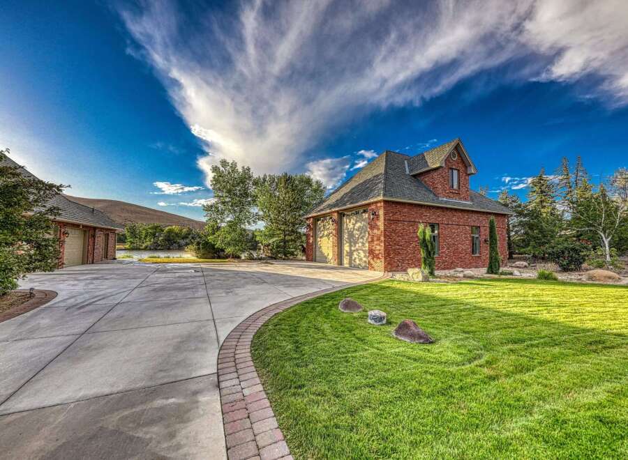 Discover this stunning brick home featuring a spacious driveway leading to a multi-car garage.